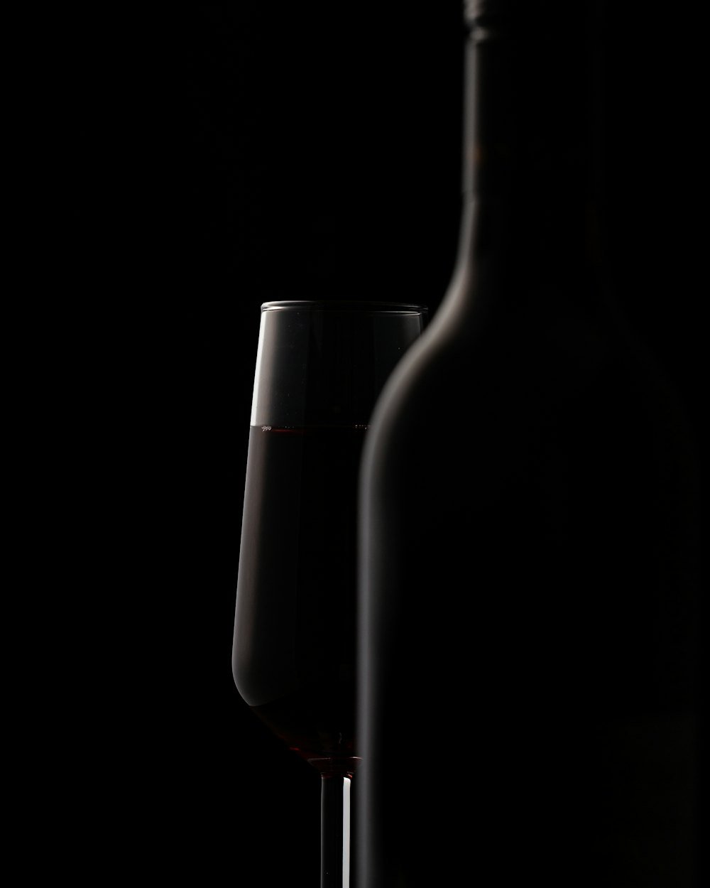 Bouteille de Bourgogne Pinot Noir La Combe Sèche et un verre de vin rouge sur fond noir